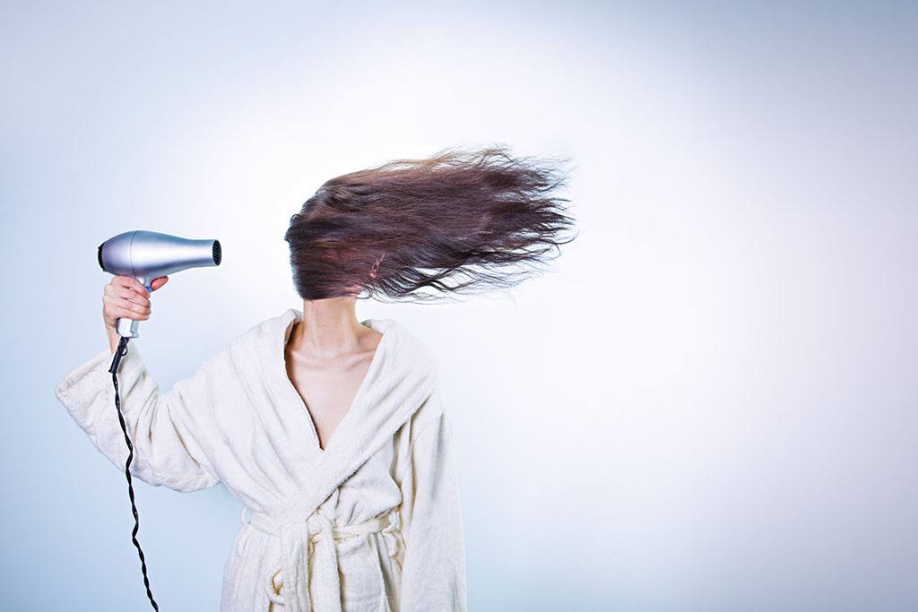 Une femme utilise un sèche cheveux