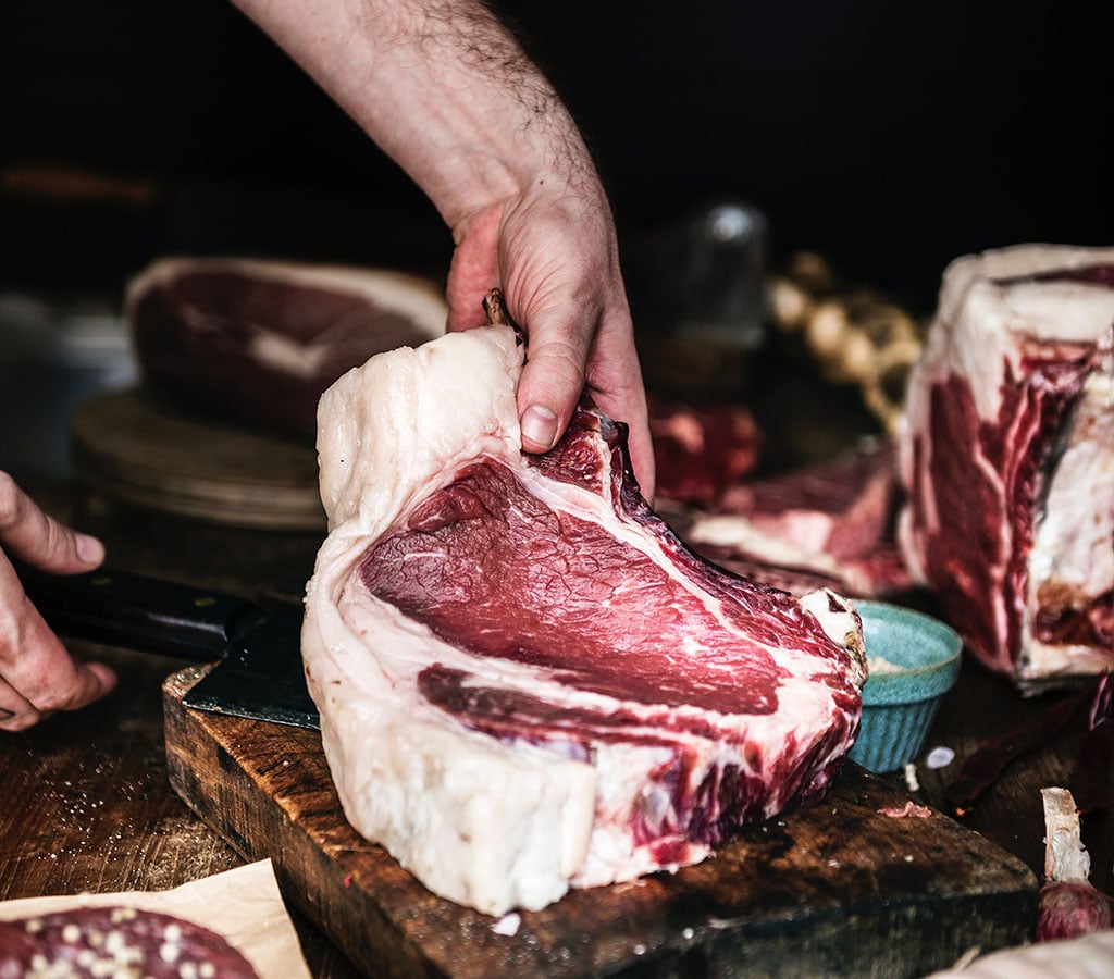 Un apprenti en boucherie découpe de la viande